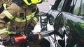 Firefighter using jaws of life to extricate trapped victim from the car