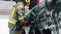 Firefighter using jaws of life to extricate trapped victim from the car