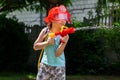 Firefighter, young child, little school age girl wearing a fireman helmet playing with a water gun in the garden. Dreams Royalty Free Stock Photo