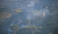 Firefighters battling a wildfire burning a forest of trees on a mountain.