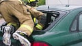 Firefighters beraking glass on car and going inside to extricate trapped victim from the car