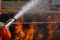 Firefighters extinguish the fire with chemical foam coming from the fire engine through a long hose