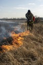 Firefighters extinguish the flames of burning grass