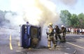 Firefighters fighting a car fire where a car i s flipped overs Royalty Free Stock Photo