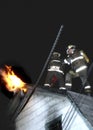 Firefighters fighting a house fire wiith flames through roofg