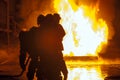 Firefighters in front of burning tank during firefighting exercise