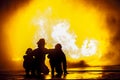 Firefighters in front of a burning tank