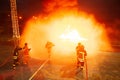 Firefighters - Firefighters put out a large fire. They were standing in protective clothing in front of a wall of fire. Royalty Free Stock Photo