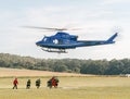 Firefighters run to fill Water bag under police helicopter