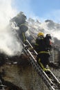 Firefighters tackle a fire on a cottage roof.