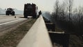 Firefighters uncoil a fire hose from a fire truck across the road to extinguish a fire in the forest and fire dry grass