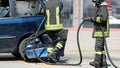 firefighters in uniform with helmets extinguish the fire of the wrecked car after the car accident