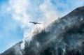 Firefighting Aircraft dropping the water for fighting a fire on mountain above Lake Ghirla in Valganna, province of Varese, Italy