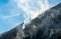 Firefighting Aircraft dropping the water for fighting a fire on mountain above Lake Ghirla in Valganna, province of Varese, Italy