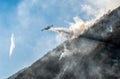 Firefighting Aircraft dropping the water for fighting a fire on mountain above Lake Ghirla in Valganna, province of Varese, Italy