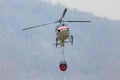 Firefighting helicopter carrying water bucket for .extinguish forest fire.