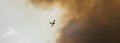 Firefighting plane flying into a large cloud of smoke Royalty Free Stock Photo