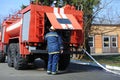 Fireman checking a water pump of a firetruck, hose attached