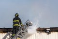 Fireman fighting a building fire at the top of an extended ladder.