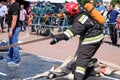 A fireman in a fireproof suit and a helmet holding a fire hose at a fire sport competition. Minsk, Belarus, 08.07.2018