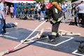 A fireman in a fireproof suit and a helmet holding a fire hose at a fire sport competition. Minsk, Belarus, 08.07.2018