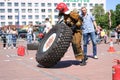 A fireman in a fireproof suit runs and turns a large rubber wheel in a fire fighting competition, Belarus, Minsk, 08.08.2018