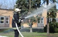 Fireman in protective costume watering plant territory with syringe - Rescue team training of firefighting