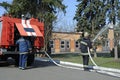 Fireman set hoses out, another one checking a water pump during training