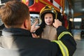 A fireman shows his work to his young son. A boy in a firefighter's helmet Royalty Free Stock Photo