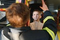 A fireman shows his work to his young son. A boy in a firefighter& x27;s helmet Royalty Free Stock Photo
