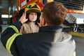 A fireman shows his work to his young son. A boy in a firefighter's helmet Royalty Free Stock Photo