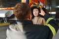 A fireman shows his work to his young son. A boy in a firefighter& x27;s helmet Royalty Free Stock Photo