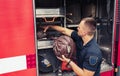 Fireman standing by fire truck, holding firefighting ropes for emergency resque operation