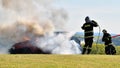 Fireman stands by a burning car and extinguishes, white smoke and flames coming out of the car Royalty Free Stock Photo