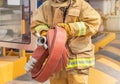 Fireman in yellow fire fighter uniform with rolled fire hose during prepare connect firehose tube in to fire hydrant