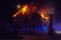 Firemen direct water stream on burning house.building in full flaming inferno, and a firefighter fighting to get control of the fl