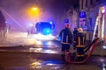 Firemen direct water stream on burning house.building in full flaming inferno, and a firefighter fighting to get control of the fl