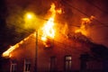 Firemen direct water stream on burning house.building in full flaming inferno, and a firefighter fighting to get control of the fl Royalty Free Stock Photo