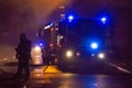 Firemen direct water stream on burning house.building in full flaming inferno, and a firefighter fighting to get control of the fl