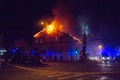 Firemen direct water stream on burning house.building in full flaming inferno, and a firefighter fighting to get control of the fl