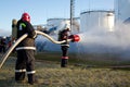 Firemen extinguish fire at oil tanks by foam spraying hose