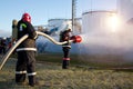 Firemen extinguish fire at oil tanks by foam spraying hose