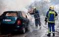 Firemen fighting a flaming car after an explosion