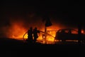 Firemen fighting vehicle fire at night Royalty Free Stock Photo