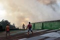 Firemen and volunteers on rooftop put out fire using fire hose during house fire that gutted interior shanty houses