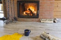 Fireplace with a blazing fire in the interior of a wooden house. Firewood and a fireplace set are located near the hearth with a Royalty Free Stock Photo