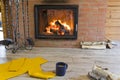 Fireplace with a blazing fire in the interior of a wooden house. Firewood and a fireplace set are located near the hearth with a Royalty Free Stock Photo