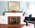 Fireplace decorated with Christmas ornaments in a room with a piano under the sunlight