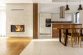 Fireplace in spacious white house interior with wooden chairs at