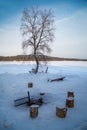 Wintery scene with with trunk stools around a fireplace in the snow.